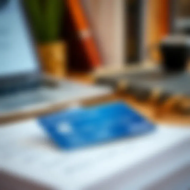 A close-up of a credit card on a desk surrounded by books and a laptop